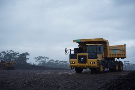 A large yellow truck drives down a dirt road

Description automatically generated with low confidence